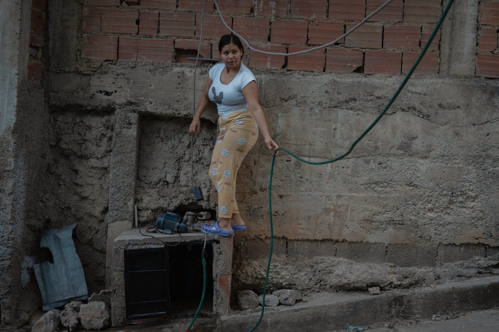 A woman picks up a pump to collect water in Petare, Caracas.