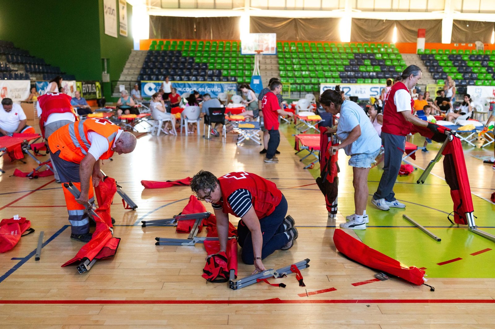 Trabajadores y voluntarios montan camas para los evacuados en el pabellón Carlos Sastre de Ávila.